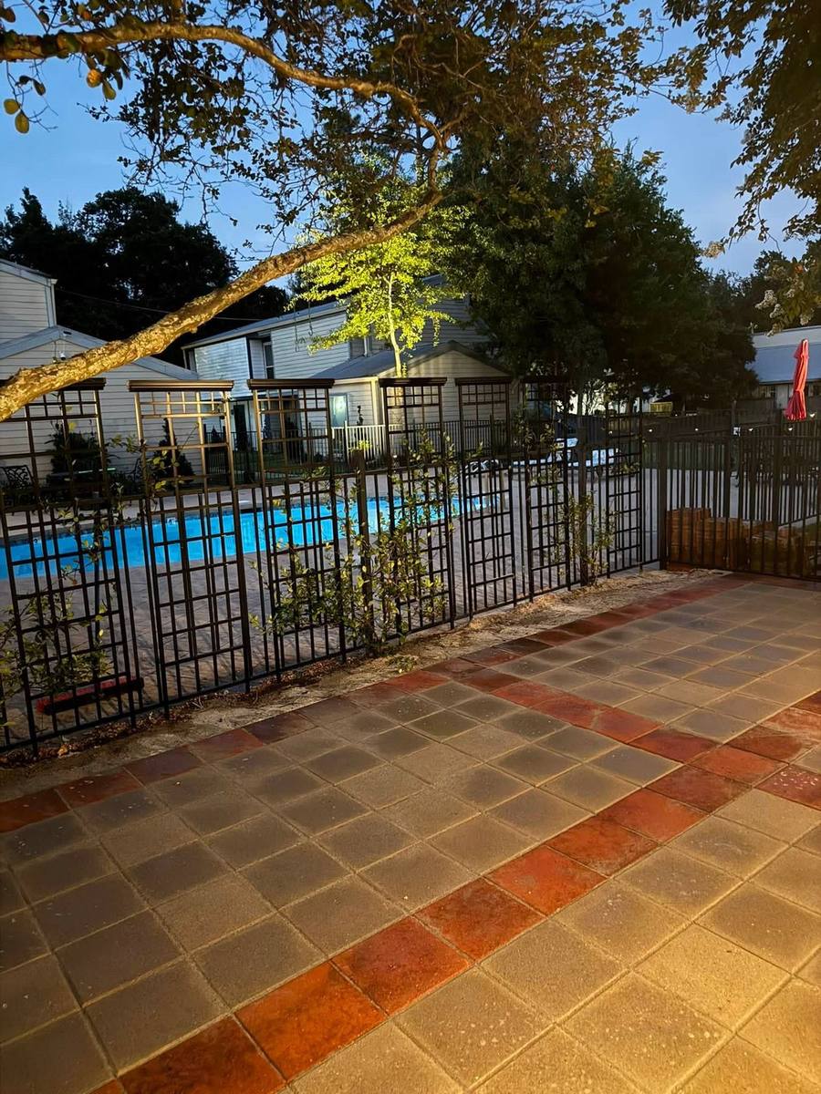 Restored paver pool deck alongside a fenced community pool in the evening